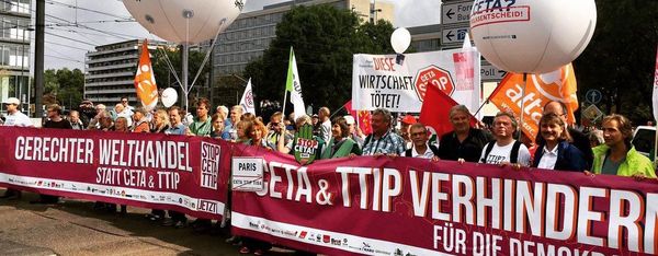 Ein Protestmarsch mit Luftballons und der Aufschrift "TTIP? CETA? Volksentscheid", ist zu sehen.