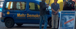 2006-bremen-demokratiemobil-paul-tiefenbach Das blaue Auto, wo "Mehr Demokratie" drauf steht, hat Besuch von einem Kamerateam.