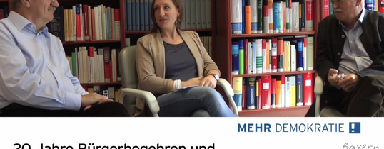bayern-jubilaeum Auf dem Bild sitzen zwei ältere Männer und eine Frau. Unter dem Bild steht "20 Jahre Bürgerbegehren und Bürgerentscheide in Bayern."