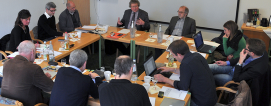 In einem Kreis sitzen circa 15 Personen und bereden Themen.