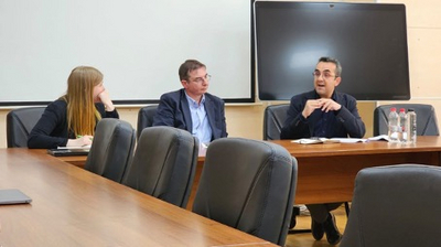 Zu sehen sind drei Personen in einem Konferenzraum.