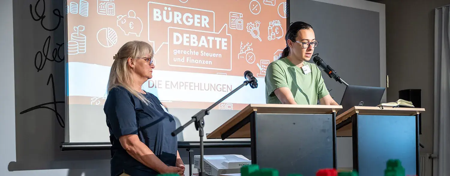 Eine junge Frau steht vor einem Rednerpult und spricht.