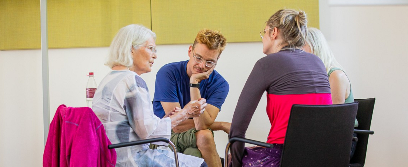 vier Personen sitzen im kreis und sprechen. 