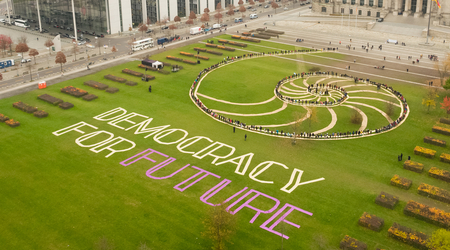 Luftaufnahme einer Menschenspirale den Schriftzug formend Democracy for Future