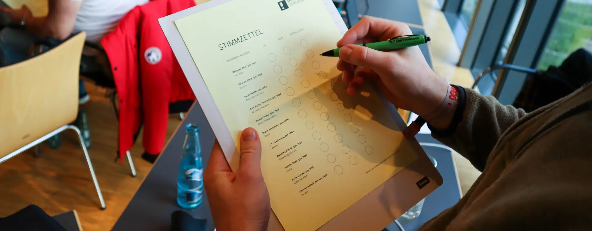 Man sieht auf einem Klemmbrett einen Stimmzettel von Mehr Demokratie, welcher gerade ausgefüllt wird.