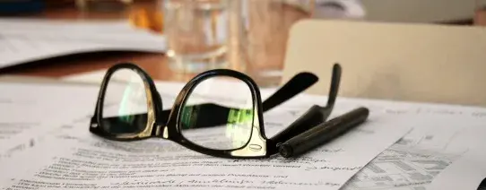 Auf dem Bild ist eine Brille um 180 Grad gedreht auf Dokumenten.