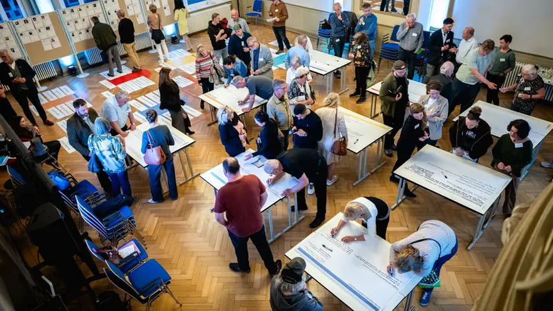 Mitglieder des Thüringer Bürgerrates "Frieden und Diplomatie" arbeiten in einem Saal stehend an Tischen und Stellwänden