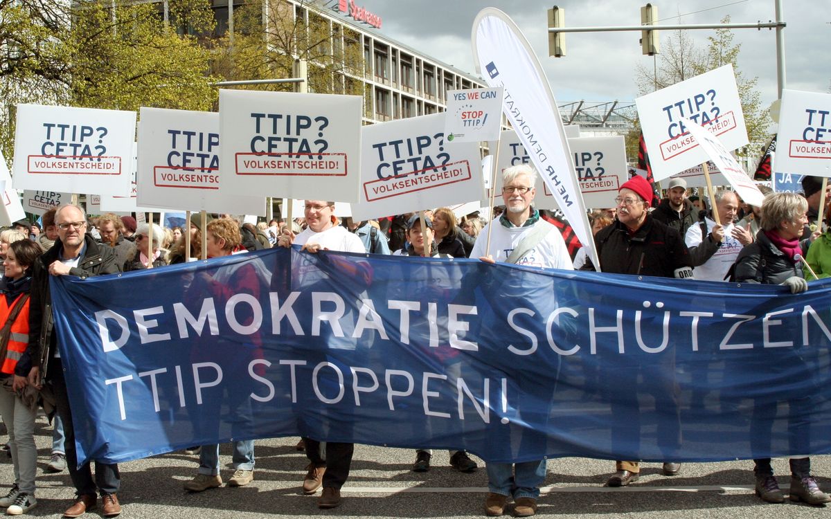 Ein blaues Transparent mit der Aufschrift "DEMOKRATIE SCHÜTZEN TTIP STOPPEN!", ist zu sehen auf dem Bild.