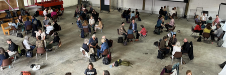 Mehrere Kleingruppen in einem großen Saal, von oben fotografiert