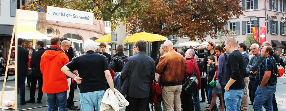 Eine Menschenmenge steht vor einem Informationstand von Mehr Demokratie.