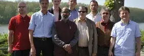 Auf dem Bild stehen neun Menschen in der Natur vor einem Fluss.