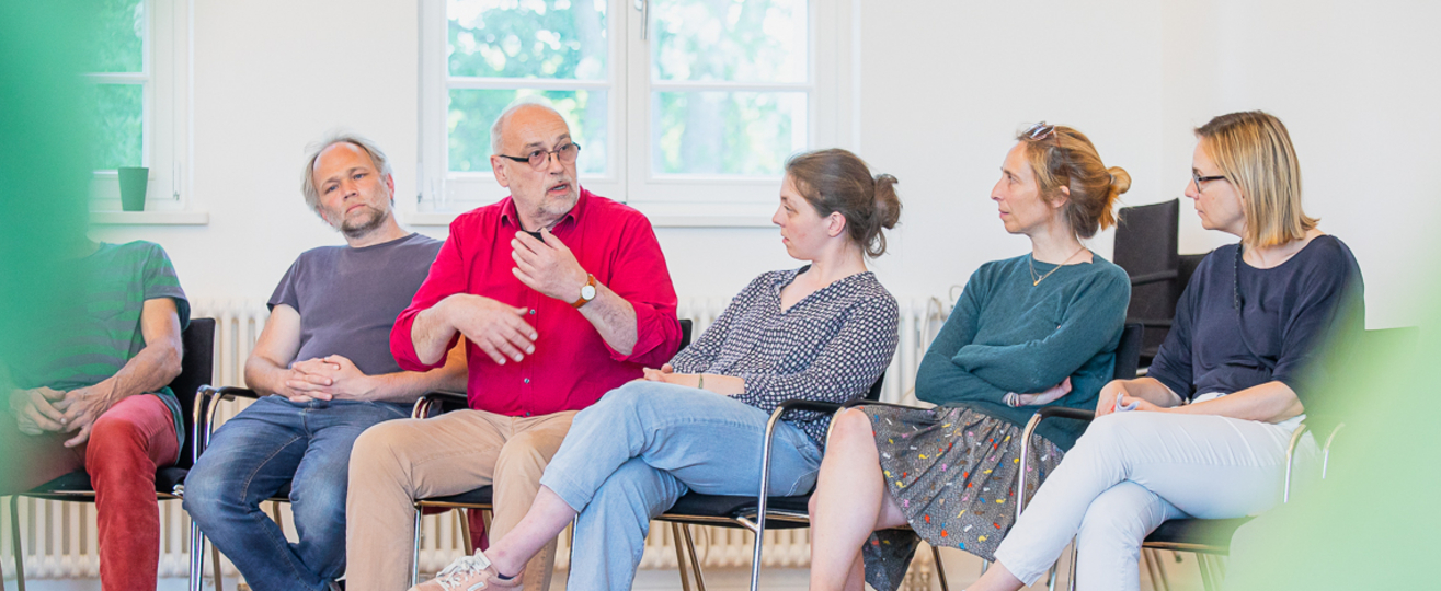 5 Menschen sitzen nebeneinander und unterhalten sich