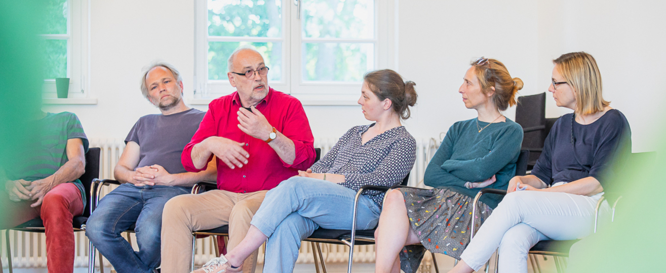 5 Menschen nebeneinander, ein Mann spricht.