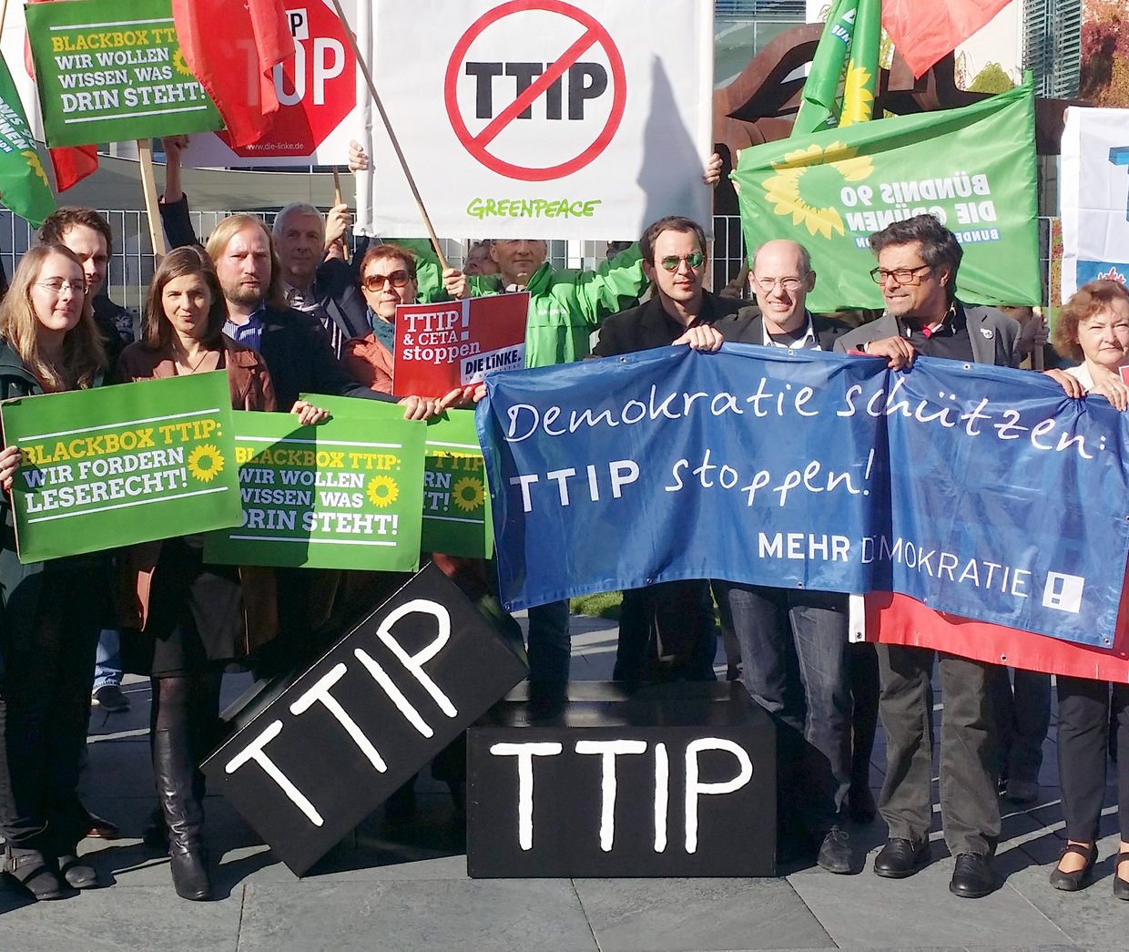 Auf dem Bild ist ein Protest gegen TTIP mit vielen unterschiedlichen Transparenten, welche unteranderem Leserecht von dem Abkommen verlangen.