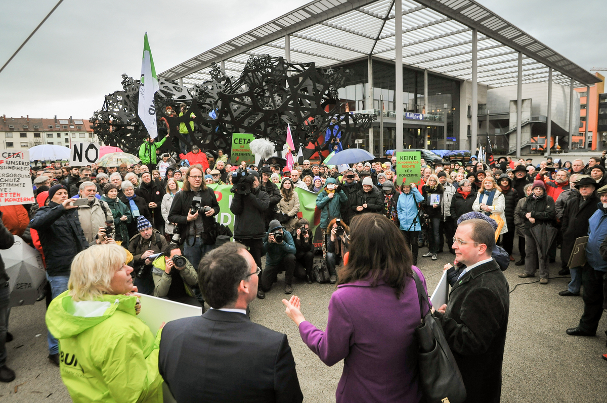Eine Frau hält eine Rede vor einer großen Menschenmasse.