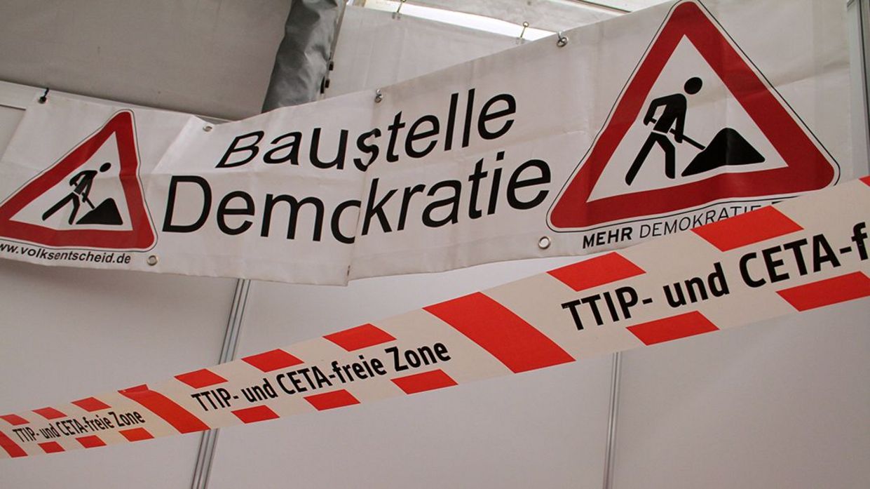 Auf einem Transparent sind Baustellenschilder abgebildet, mit dem Text "Baustelle Demokratie".