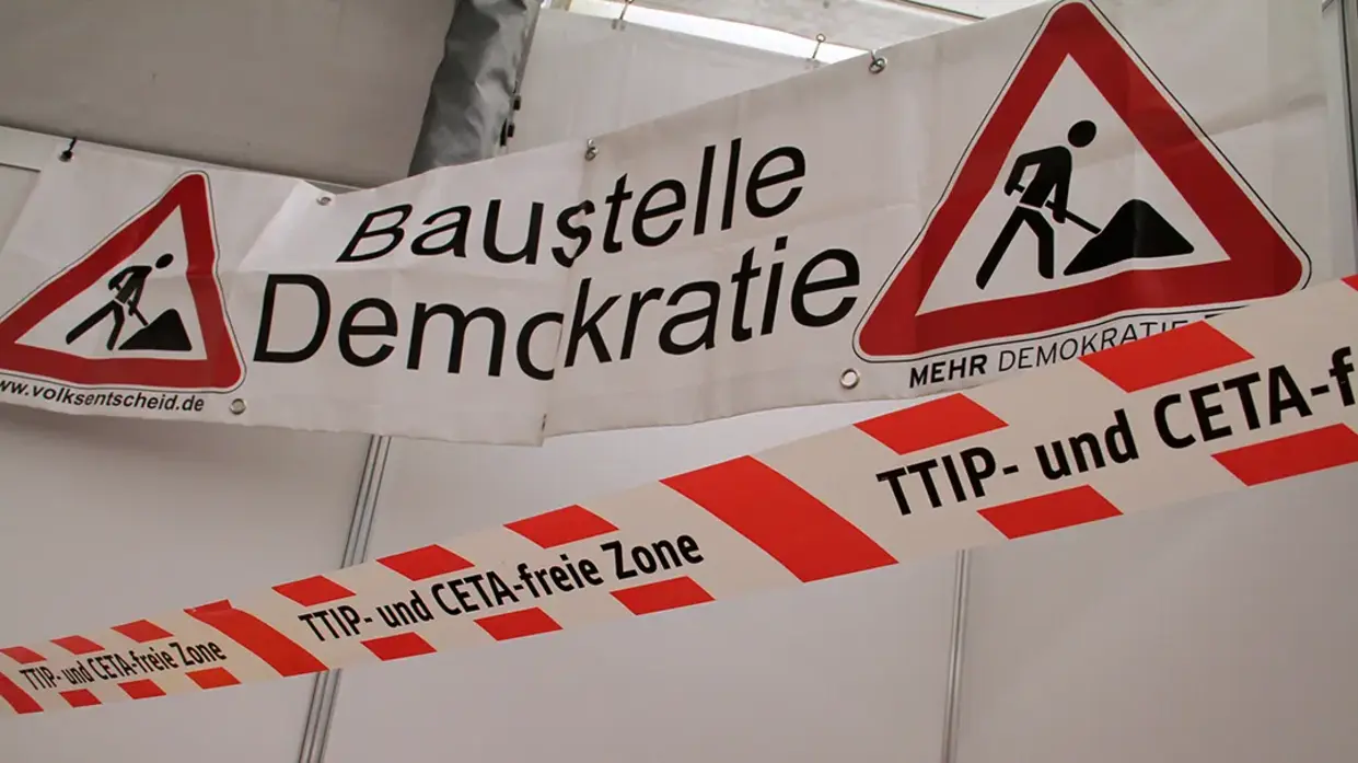 Auf einem Transparent sind Baustellenschilder abgebildet, mit dem Text "Baustelle Demokratie".