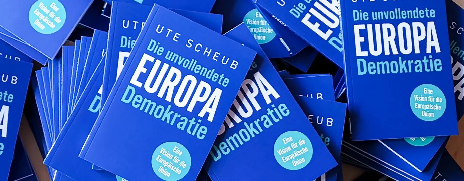 Auf dem Bild sind ganz viele Bücher von Ute Scheub, mit dem Titel "Die unvollendete EUROPA Demokratie".