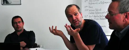 Ein Mann guckt fragend einen anderen Mann an.