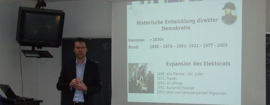 (Dr. Uwe Sedült | Foto by Cora Pfafferott | Lizenz: CC BY-NC 2.0) Dr. Uwe Sedült hält einen Vortrag vor einer Leinwand.