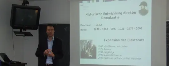 (Dr. Uwe Sedült | Foto by Cora Pfafferott | Lizenz: CC BY-NC 2.0) Dr. Uwe Sedült hält einen Vortrag vor einer Leinwand.