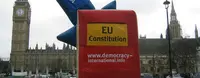 Auf dem Bild ist ein circa vier mal fünf Meter großes, aus Plastik aufgeblasenes Rechteck, mit der Aufschrift "EU Constitution", von oben steckt ein Pfeil aus Plastik darin, mit der Aufschrift "only by fair REFERENDA".