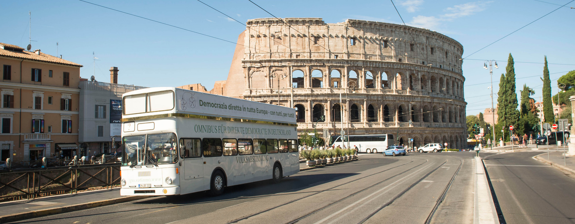 Man sieht eine Straße vor dem Kolosseum in Rom und einem Weißen OMNIBUS.