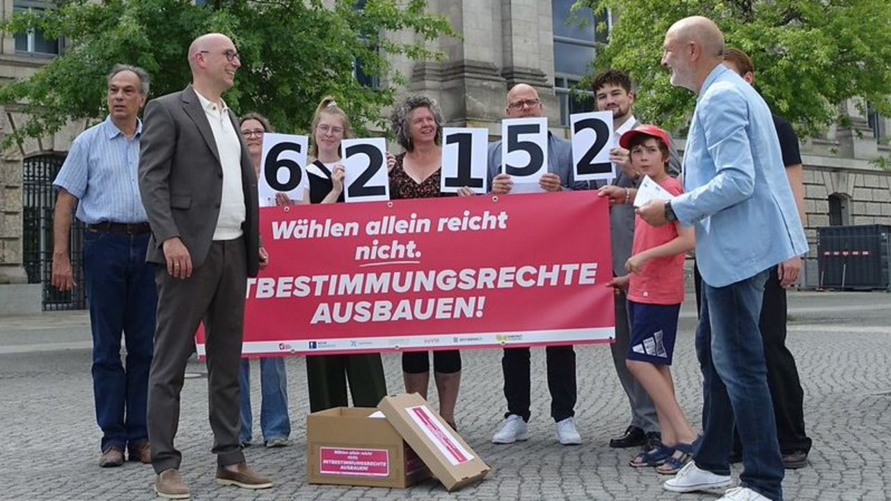 Eine Gruppe von Menschen mit einem Transparent: 62152. Wählen allein reicht nicht. Mitbestimmungsrechte ausbauen