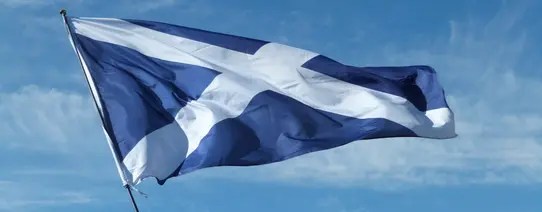 Vor einem blauen Himmel weht die Flagge von Schottland.