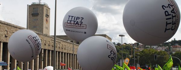 Ein Protestmarsch mit Luftballons und der Aufschrift "TTIP? CETA? Volksentscheid", ist zu sehen.