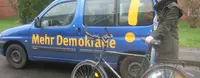 Ramona Pump ist mit einem Fahrrad vor dem Mehr Demokratie Auto.