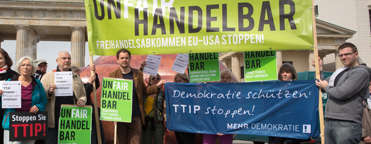 Vor dem Brandenburger Tor ist eine Protestaktion gegen TTIP. Auf einem Transparent steht "UNFAIR HANDELBAR, Absatz FREIHANDELSABKOMMEN EU- USA STOPPEN!".