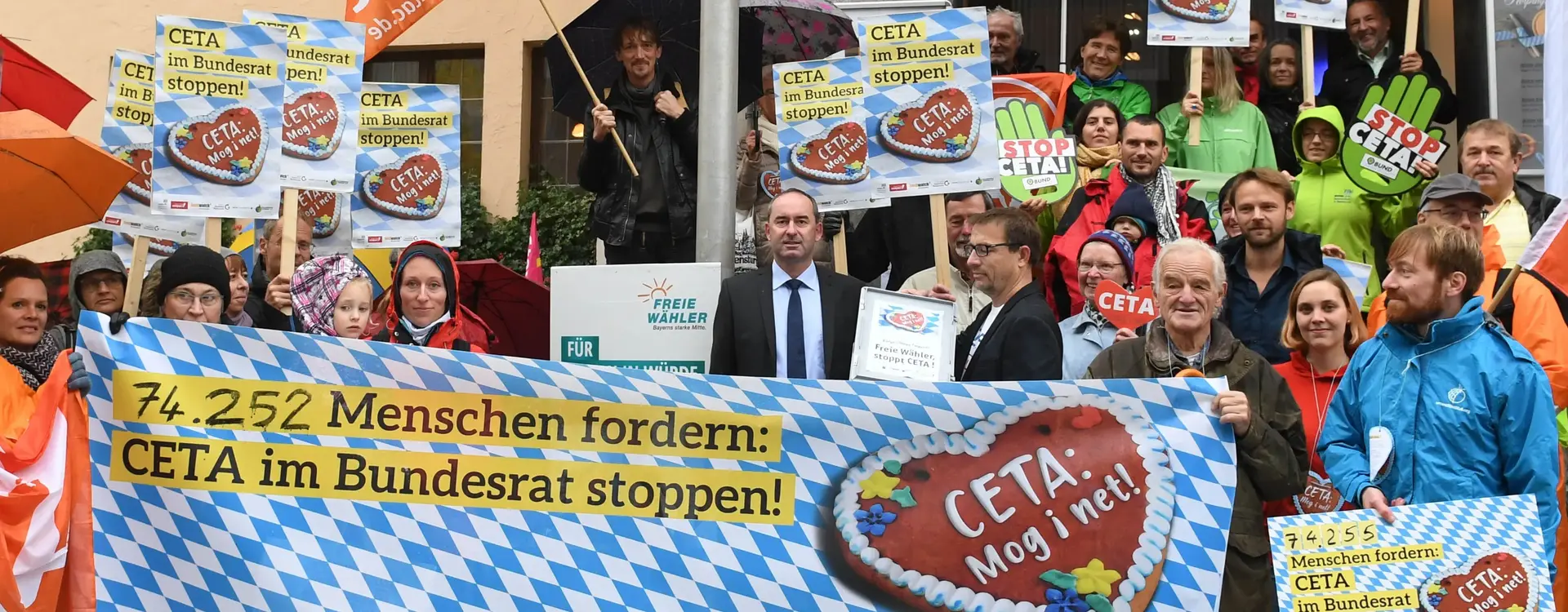 Bei einem Protest wird ein Transparent hochgehalten mit der Aufschrift "74.252 Menschen fordern: CETA im Bundesrat stoppen!".
