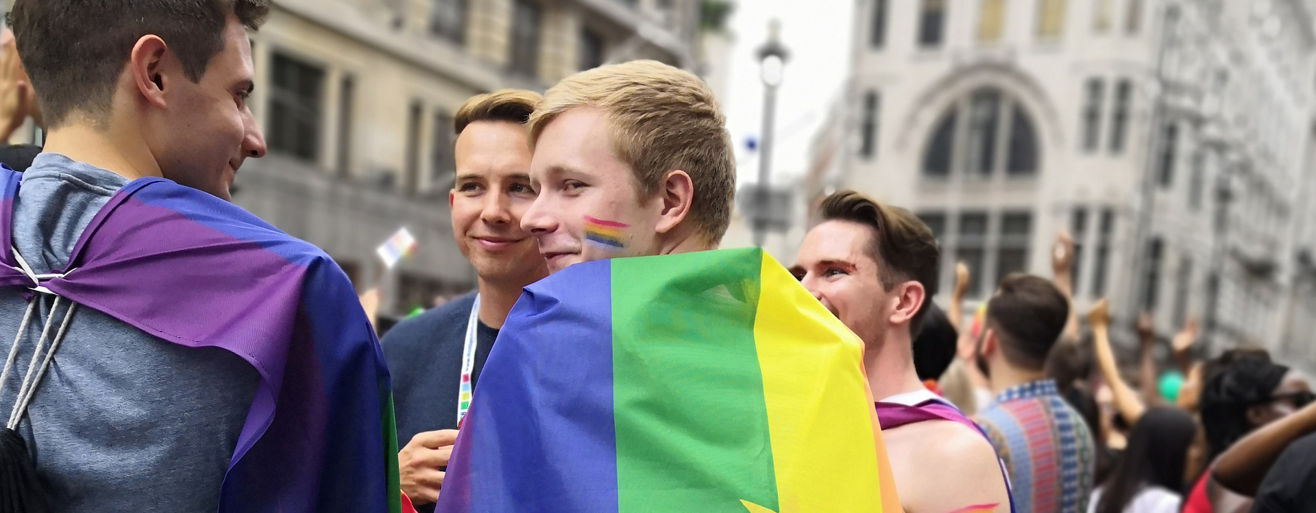 Überschrift: Wahlrecht. Man sieht eine Gruppe junger Menschen, mit Regenbogenfahnen und Regenbögen auf den Gesichtern. Alle Menschen auf dem Bild lächeln oder lachen