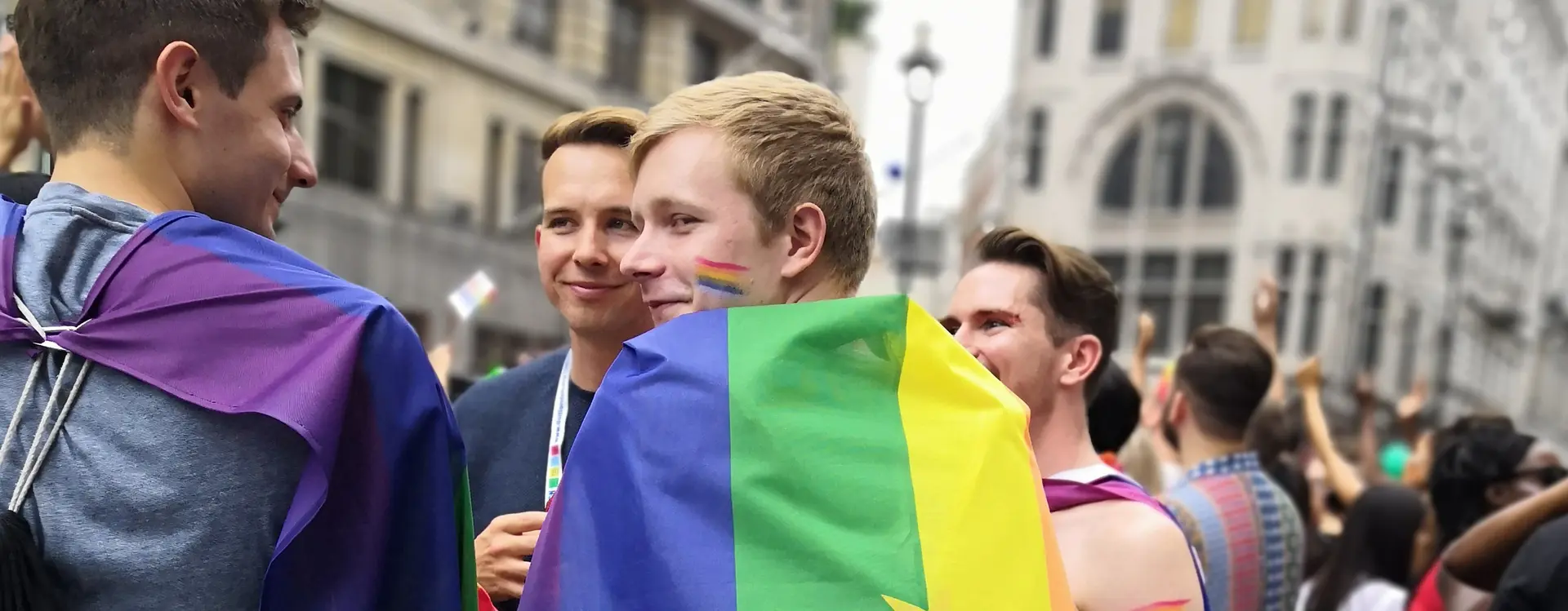Überschrift: Wahlrecht. Man sieht eine Gruppe junger Menschen, mit Regenbogenfahnen und Regenbögen auf den Gesichtern. Alle Menschen auf dem Bild lächeln oder lachen
