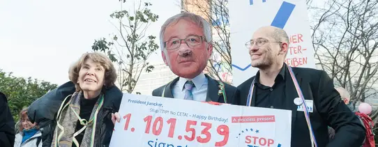 (Copyright: FKPH) Zu sehen ist ein Protestmarsch, gegen TTIP und einem Schild, welches 1.101.539 Unterschriften gegen TTIP gesammelt hat darstellt.