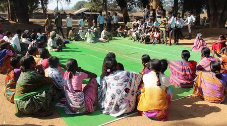 Bewohnerinnen und Bewohner des indischen Dorfes Mendha Lekha sitzen im Freien unter Bäumen zu einer Gram Sabha zusammen. In der Dorfversammlung beraten die Bürgerinnen und Bürger gemeinschaftlich über Angelegenheiten ihres Dorfes