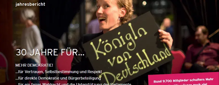 Auf dem Bild ist eine frau, die ein Schild hochhält mit dem Text "Königin von Deutschland". Links-oben steht "2018 jahresbericht". Links-unten steht "30 JAHRE für... MEHR DEMOKATIE! ... für Vertrauen, Selbstbestimmung und Respekt, ... für direkte Demokratie und Bürgerbeteiligung, ... für ein faires Wahlrecht und die Unterstützung der Parlamente, ...für Mehr Demokratie in der EU, ...für das neue in der Demokratie".