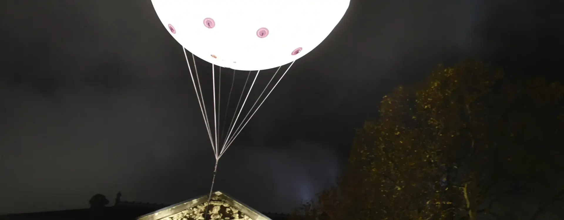 Ein Helium Luftballon , welcher beleuchtet in der Nacht die Aufschrift "Volksabstimmung" verlautet, ist zu sehen.