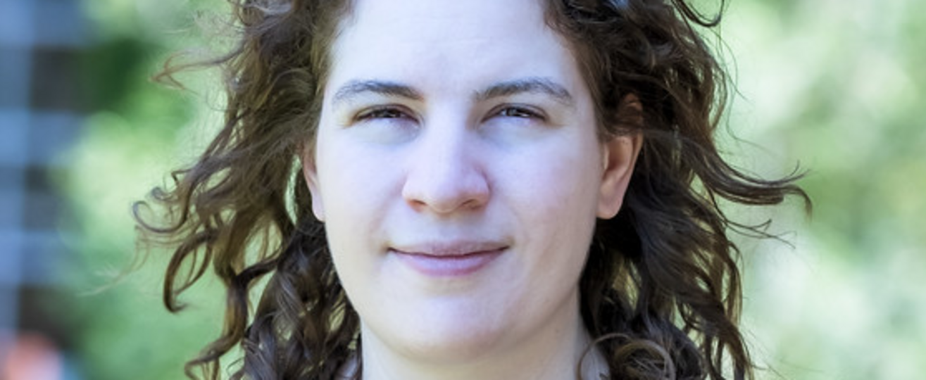 Porträtfoto von Leonora Camner in einem dunkelblauen Oberteil mit Kirsch-Muster