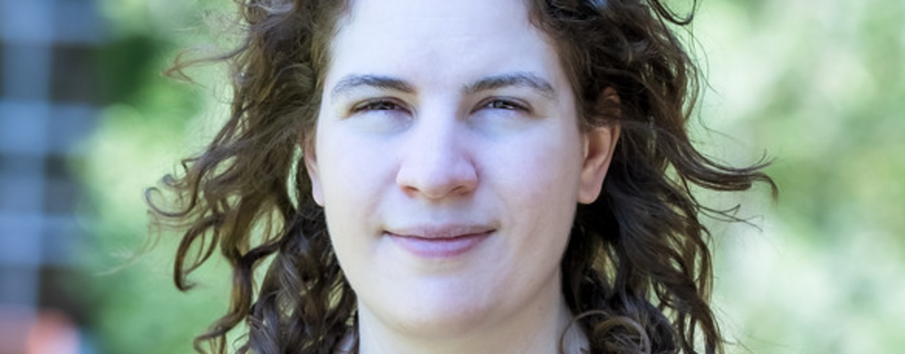 Porträtfoto von Leonora Camner in einem dunkelblauen Oberteil mit Kirsch-Muster