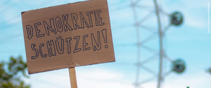 Auf einem Pappplakat steht "Demokratie schützen!".