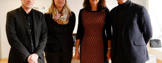 Vier Menschen stehen auf diesem Bild nebeneinander.