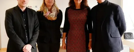 Vier Menschen stehen auf diesem Bild nebeneinander.