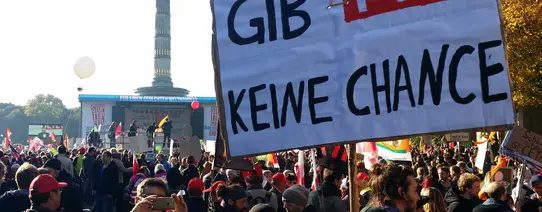 Auf einem Protest wird ein Plakat mit der Aufschrift "GIB TTIP KEINE CHACE" hochgehalten.