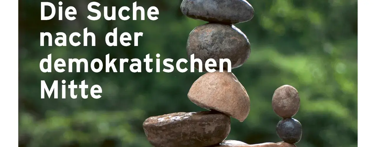 Zu sehen ist das Deckblatt von der Magazin Ausgabe vom 01.2025. Auf dem Bild sieht man einen Steinturm, der sehr wackelig aussieht, aber ausbalanciert ist. Links-mittig im Vordergrund steht: Die Suche nach der demokratischen Mitte