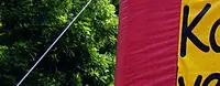 Auf dem Bild ist ein circa vier mal fünf Meter großes, aus Plastik aufgeblasenes Rechteck, mit der Aufschrift "Kommunale-verfassung", von oben steckt ein Pfeil aus Plastik darin, mit der Aufschrift "Faire Volksentscheide".