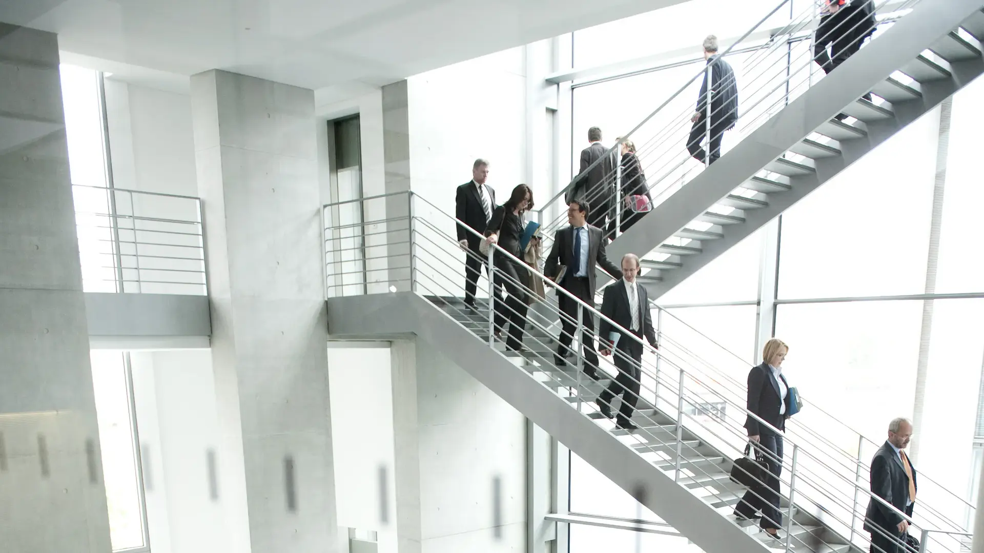 Viele Menschen laufen in einem Anzug eine Treppe herunter.