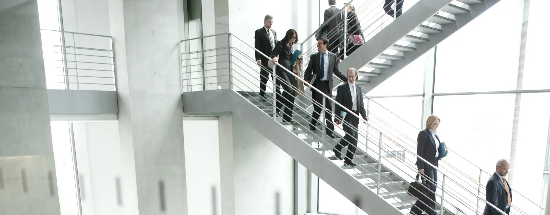 Menschen in Anzügen laufen eine Treppe herunter.