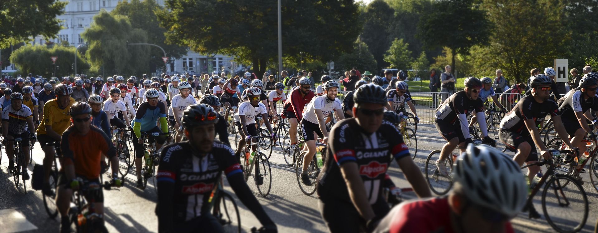 Die Fahrradfahrer mit dem "TTIP? CETA? Volksentscheid" Aufdruck auf ihrem T-Shirt fahren über eine abgesperrte breite Straße.